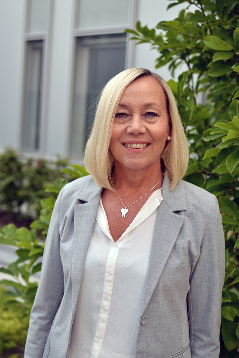 Leende kvinna i vit skjorta och beige kavaj