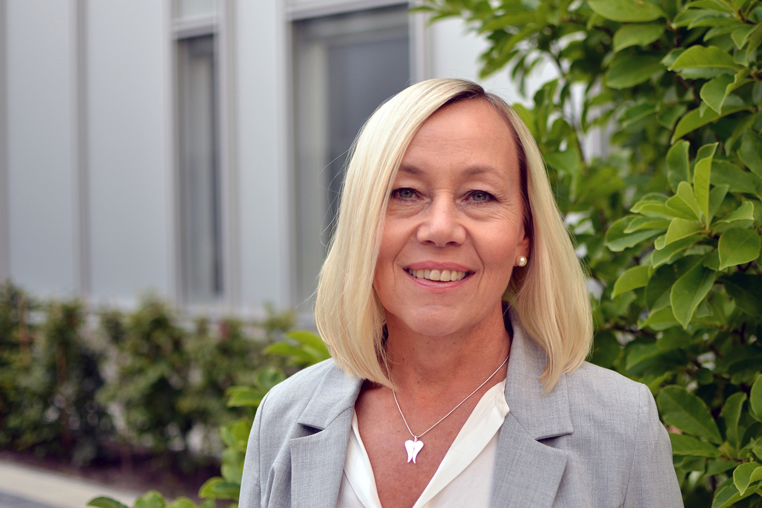 Leende kvinna i vit skjorta och beige kavaj