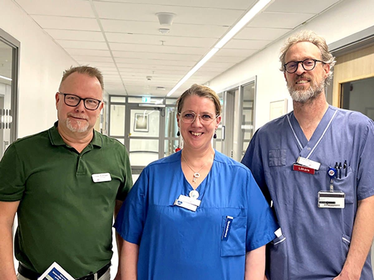 Tre glada personer ståendes i en korridor