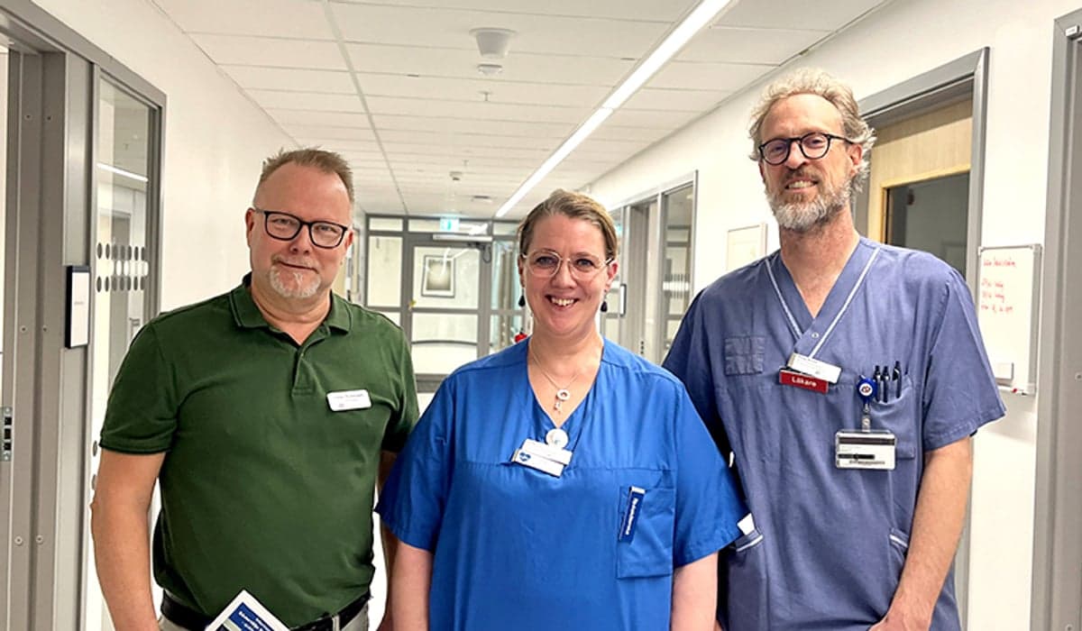 Tre glada personer ståendes i en korridor