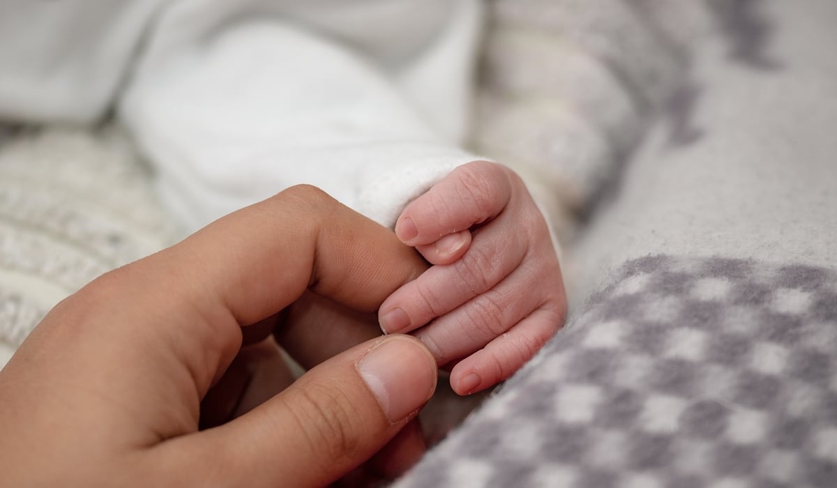 En vuxen hand som håller i en bebishand