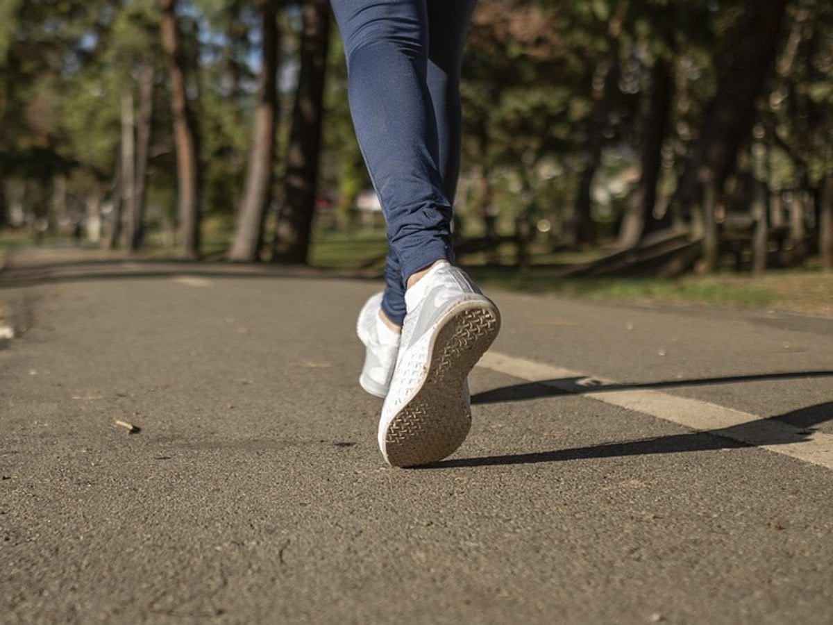 En person som går längs en väg med träd i bakgrunden