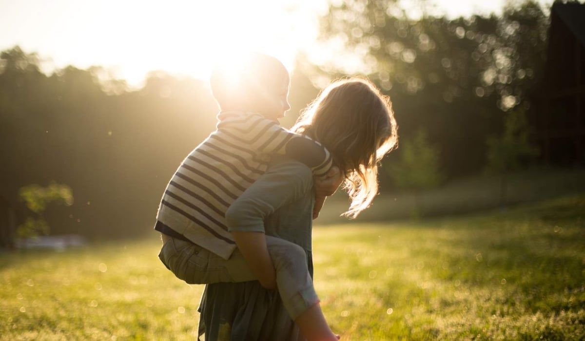 Ett barn som bär ett mindre barn ute i naturen