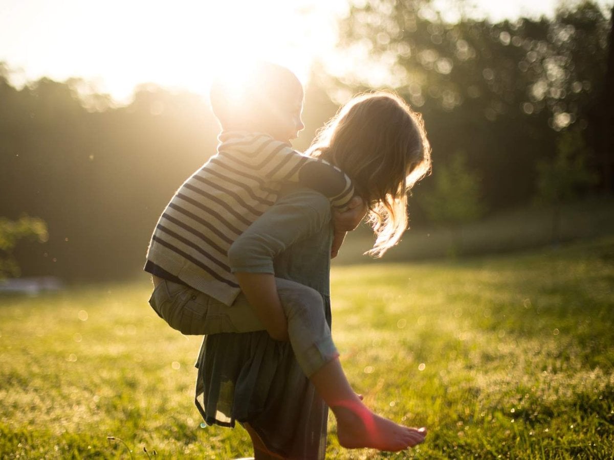 Ett barn som bär ett mindre barn ute i naturen