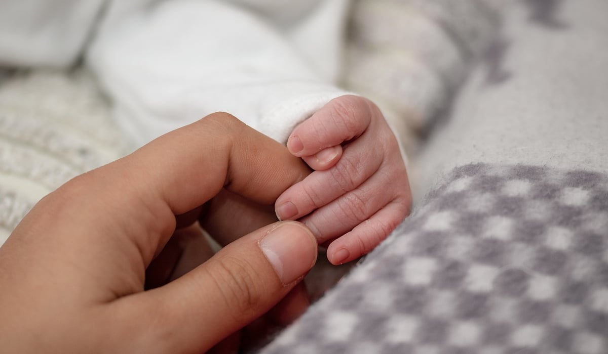 En vuxen hand som håller i en bebishand