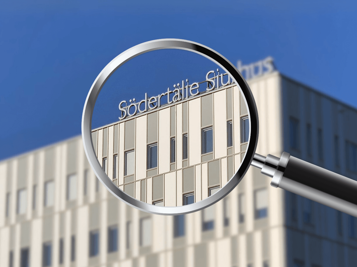 Ett förstoringsglas som förstorar loggan på fasaden av Södertälje sjukhus