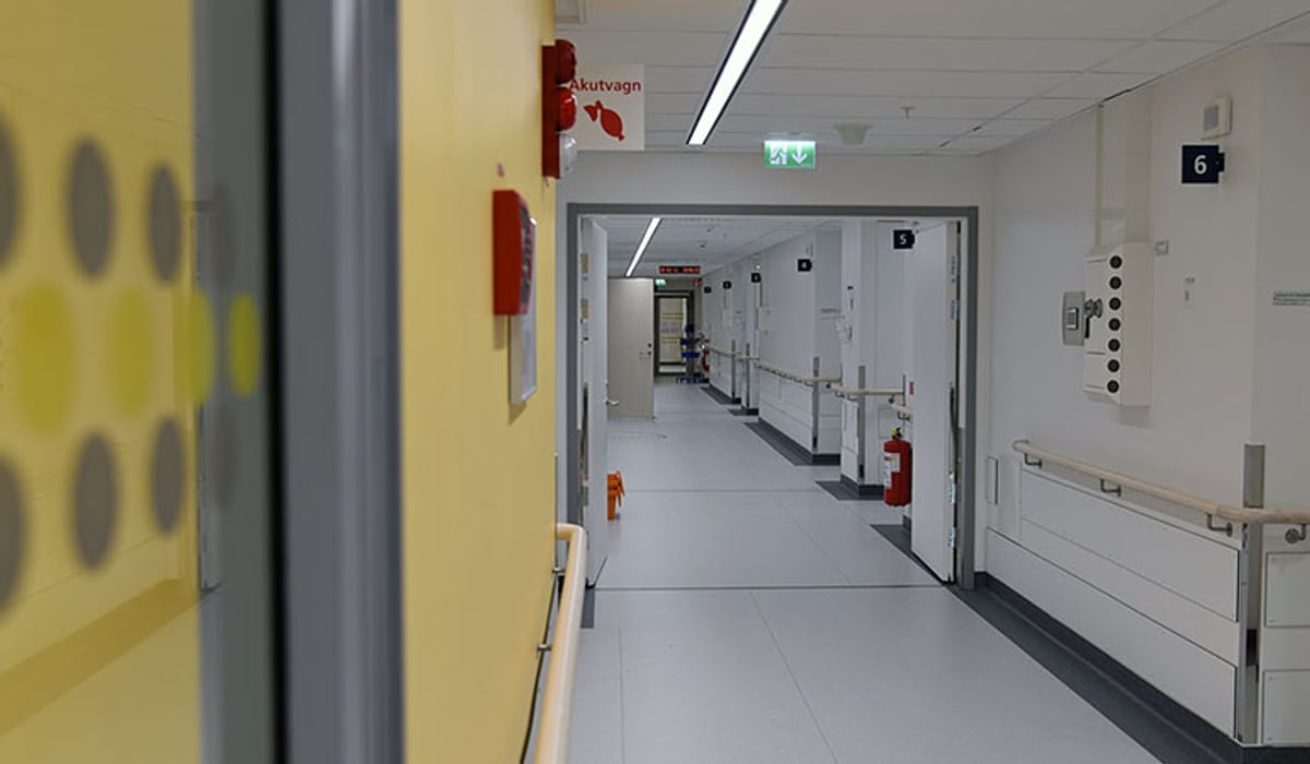 En lång korridor med gula dörrar och vita väggar