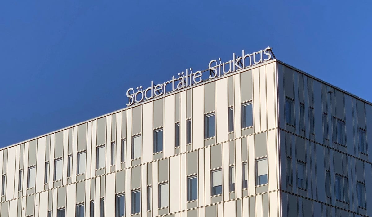 Södertälje sjukhus exteriör med loggan mot en blå himmel