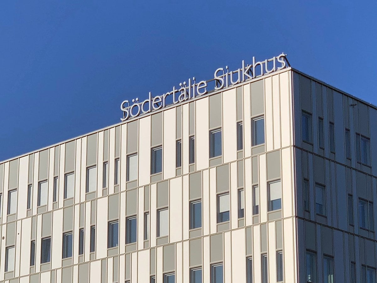 Södertälje sjukhus exteriör med loggan mot en blå himmel