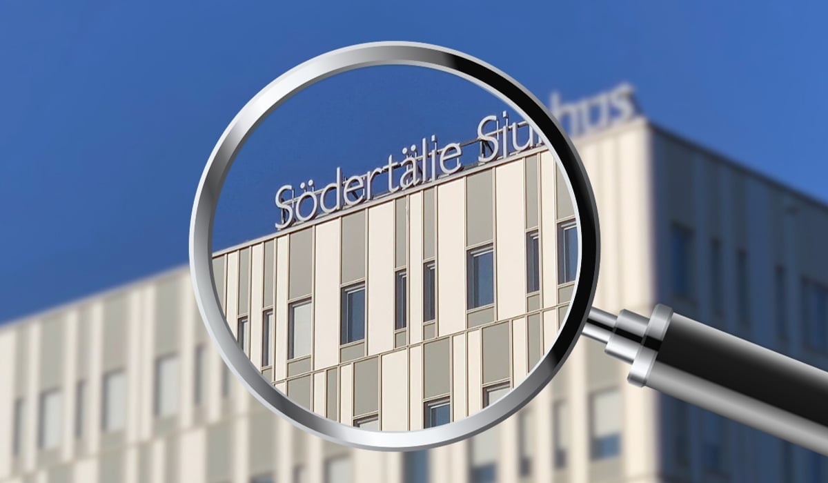 Ett förstoringsglas som förstorar loggan på fasaden av Södertälje sjukhus