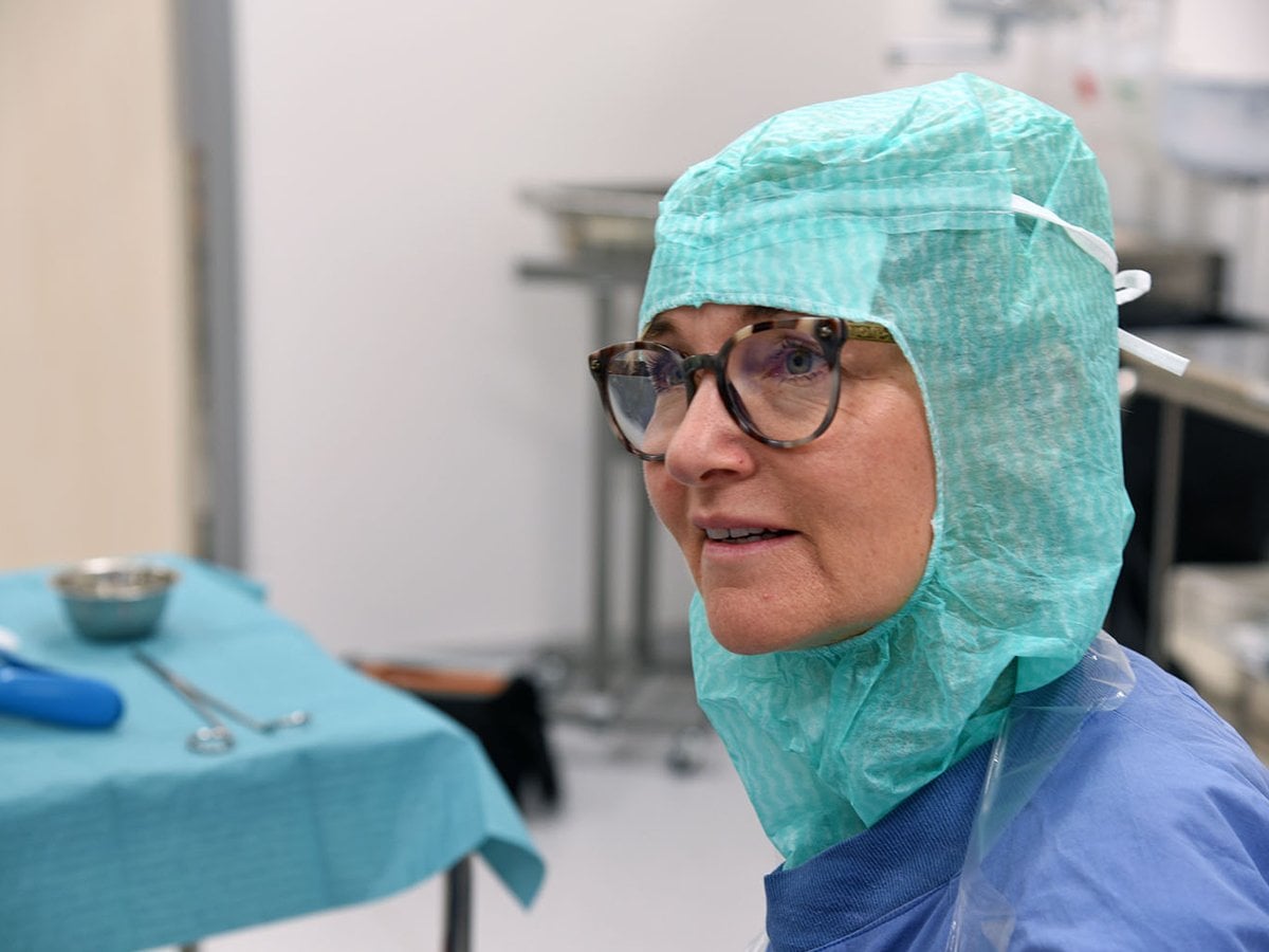 En kvinna iförd kirurgisk mask och glasögon