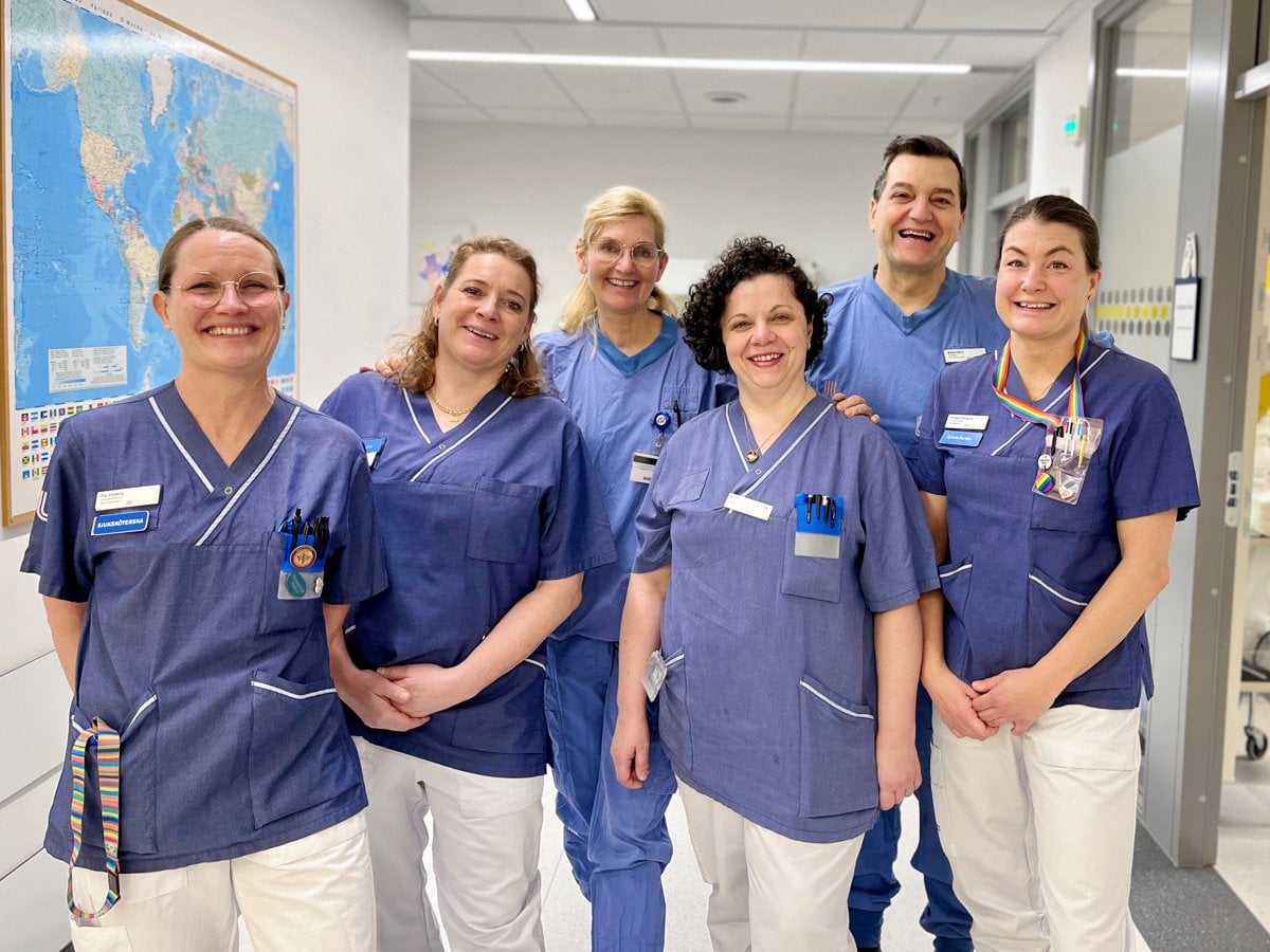 En grupp i blå vårdkläder som står i en sjukhuskorridor