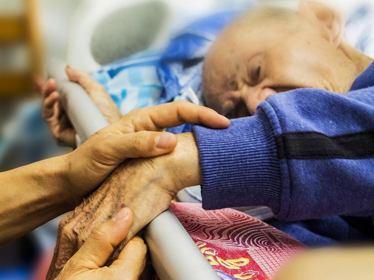 Händer som håller en gammal mans hand.