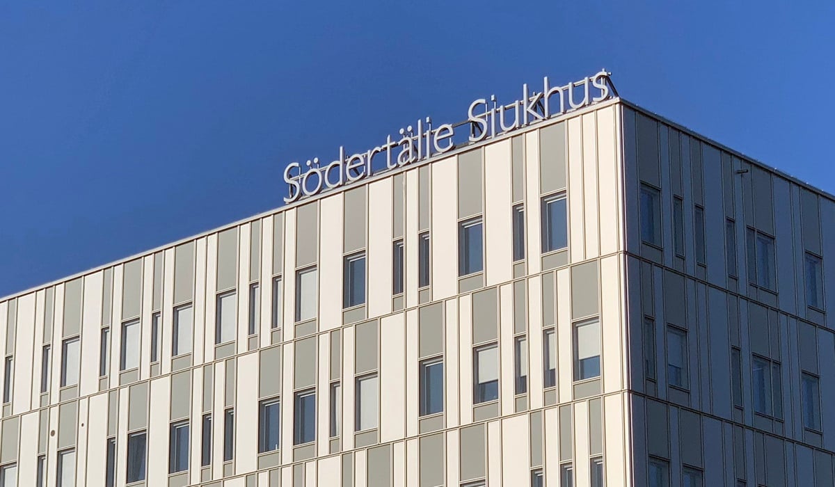 Södertälje sjukhus exteriör med loggan mot en blå himmel