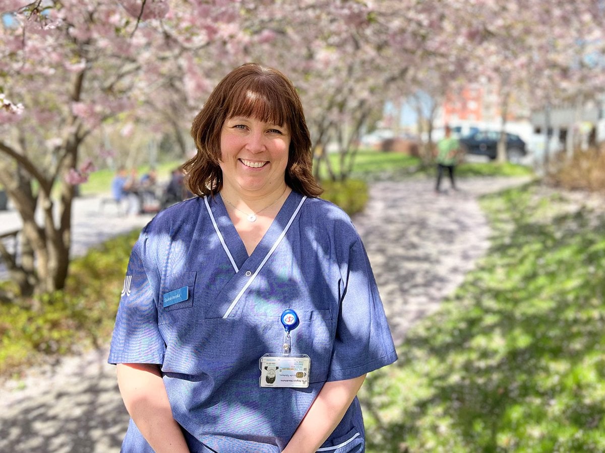 Glad sjuksköterska ståendes framför ett körsbärsträd.