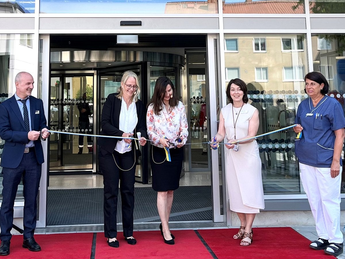 Fyra personer som håller ett band vid huvudentrén medan en femte klipper bandet