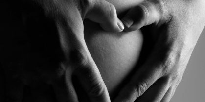 Två händer håller om en gravidmage