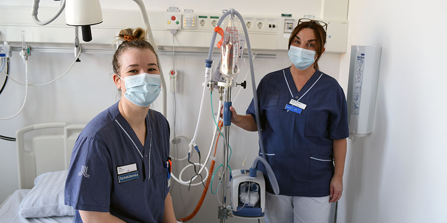 Två medarbetare står i ett patientrum med utrustning mellan sig.