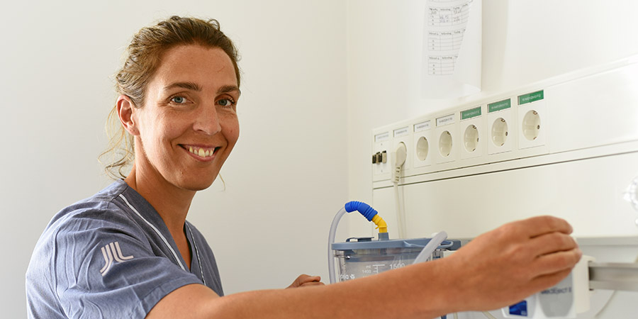 Glad medarbetare kontrollerar utrustning i patientrum